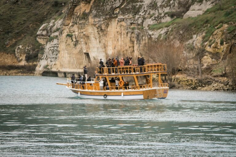 A ferry boat carrying passengers navigates a scenic rocky coastline. Ideal for travel and adventure themes.