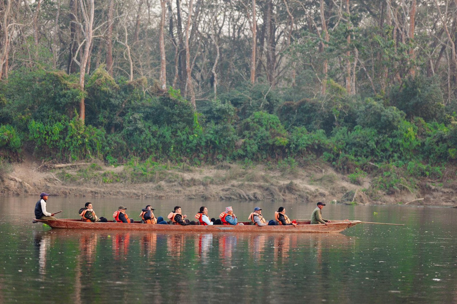 A group of tourists in a wooden canoe paddling along a calm forest river. Perfect for travel promotions.