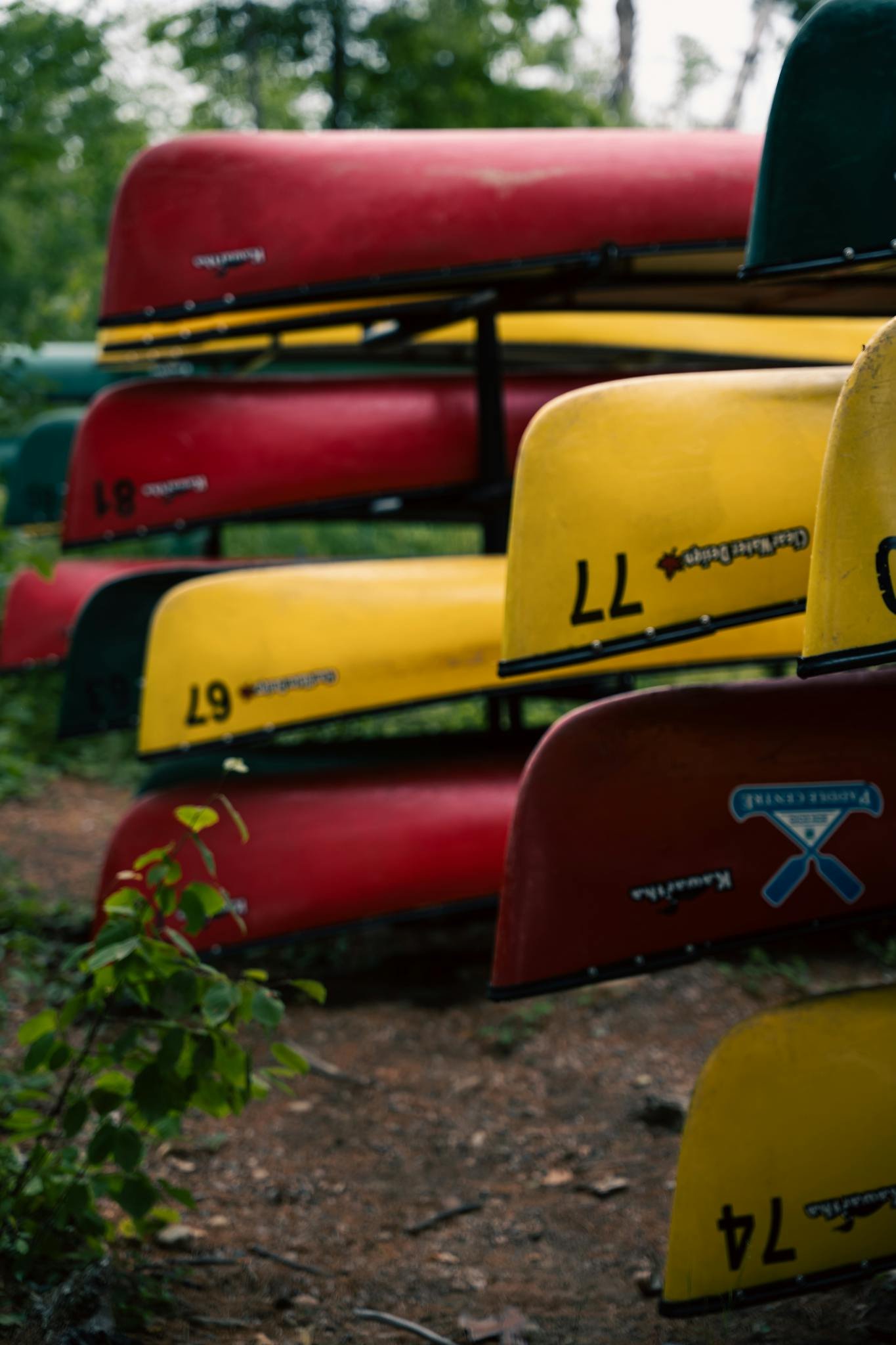 Vibrant red and yellow canoes stacked in an outdoor natural environment.